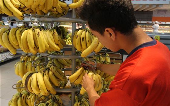 Homem pega cachos de banana em supermercado