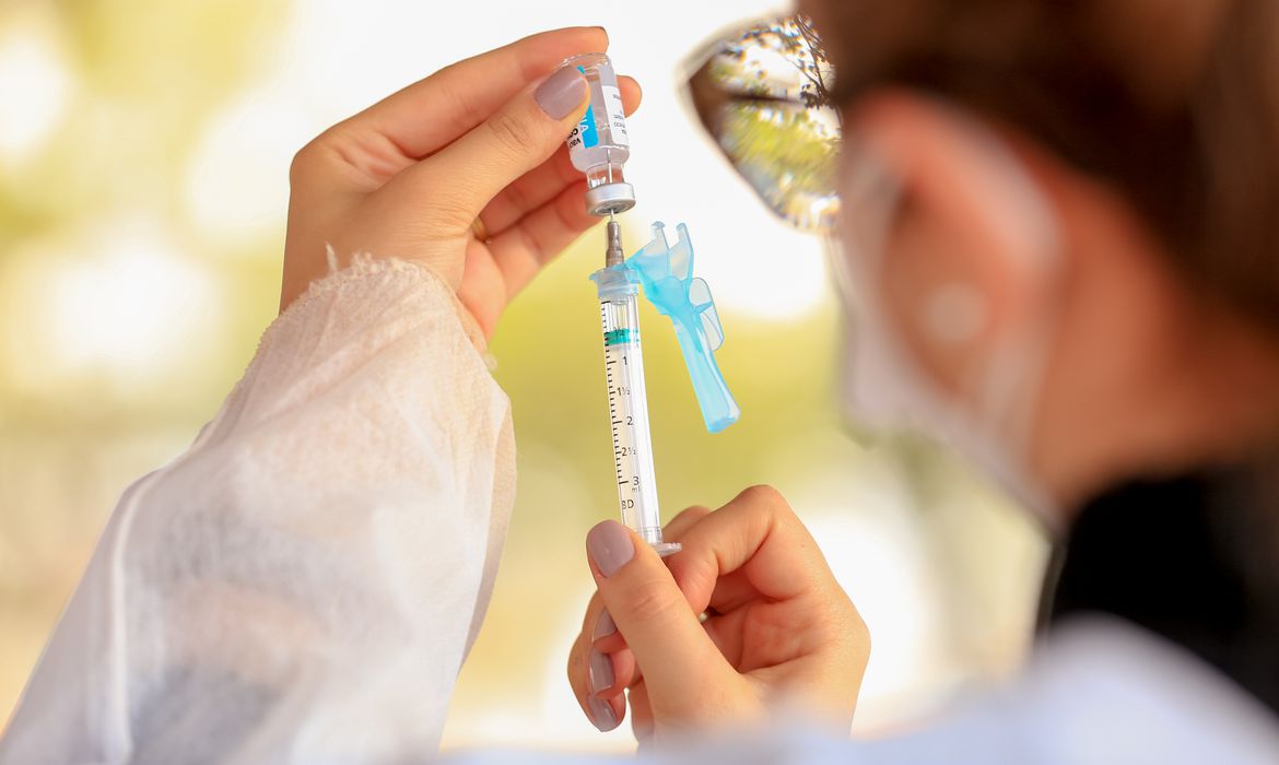 enfermeira segurando uma agulha com dose da vacina contra a covid-19