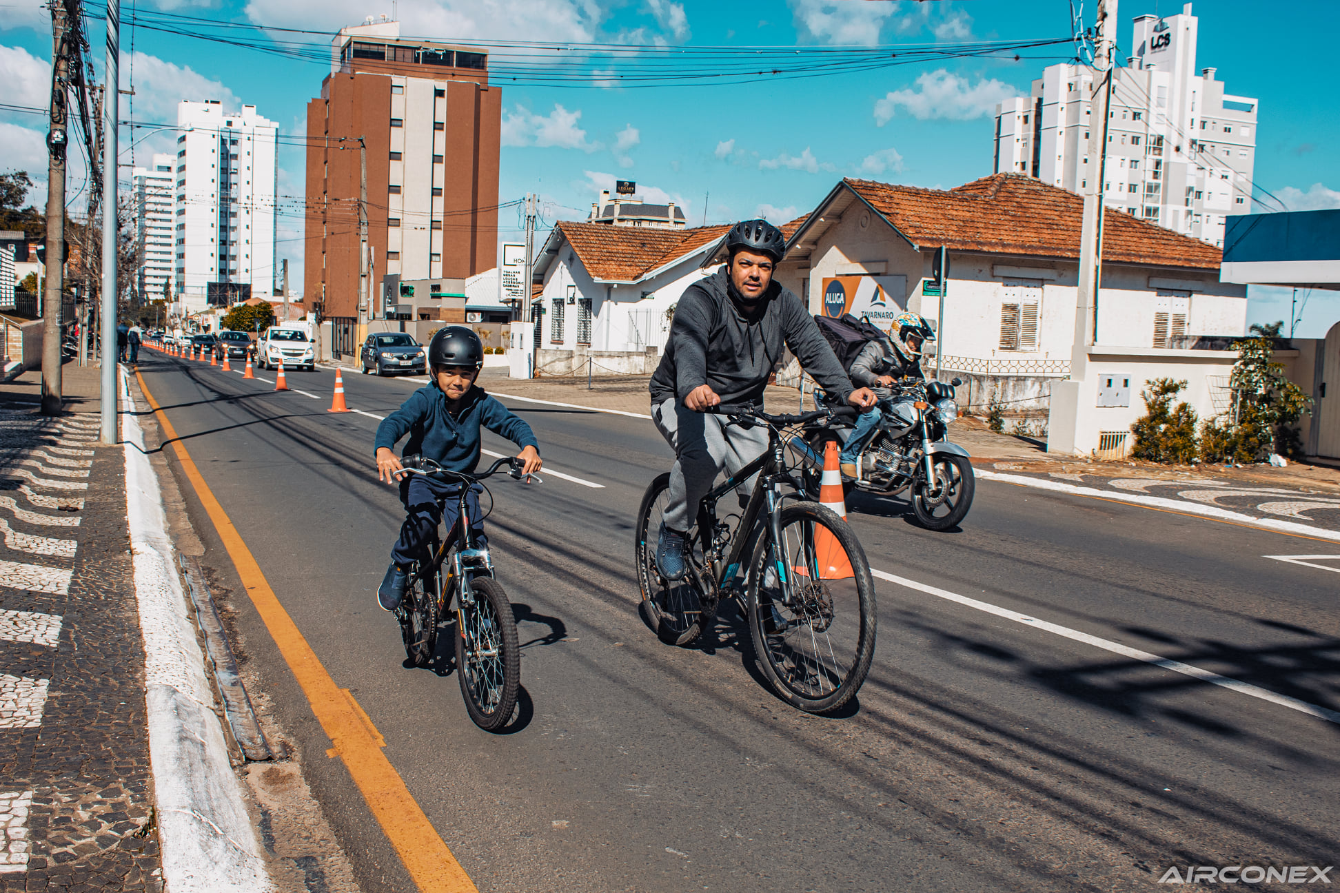 Criança e seu pai andando de bicicleta durante o projeto Avenida Central.