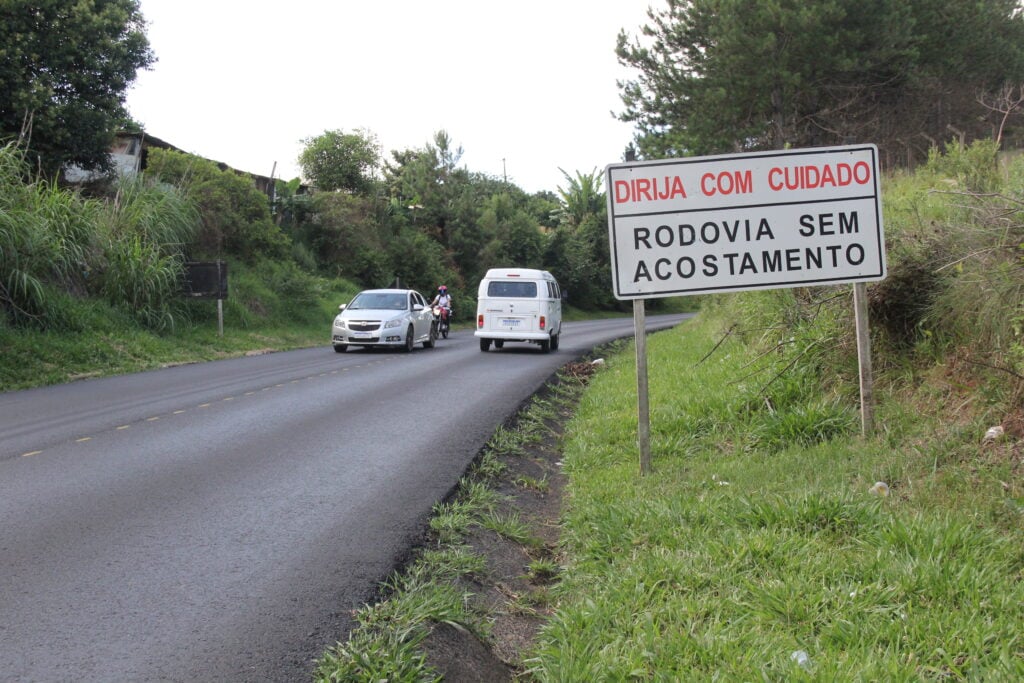 Foto de placa alertando para falta de acostamento na rodovia PR-151, em Ponta Grossa, Paraná