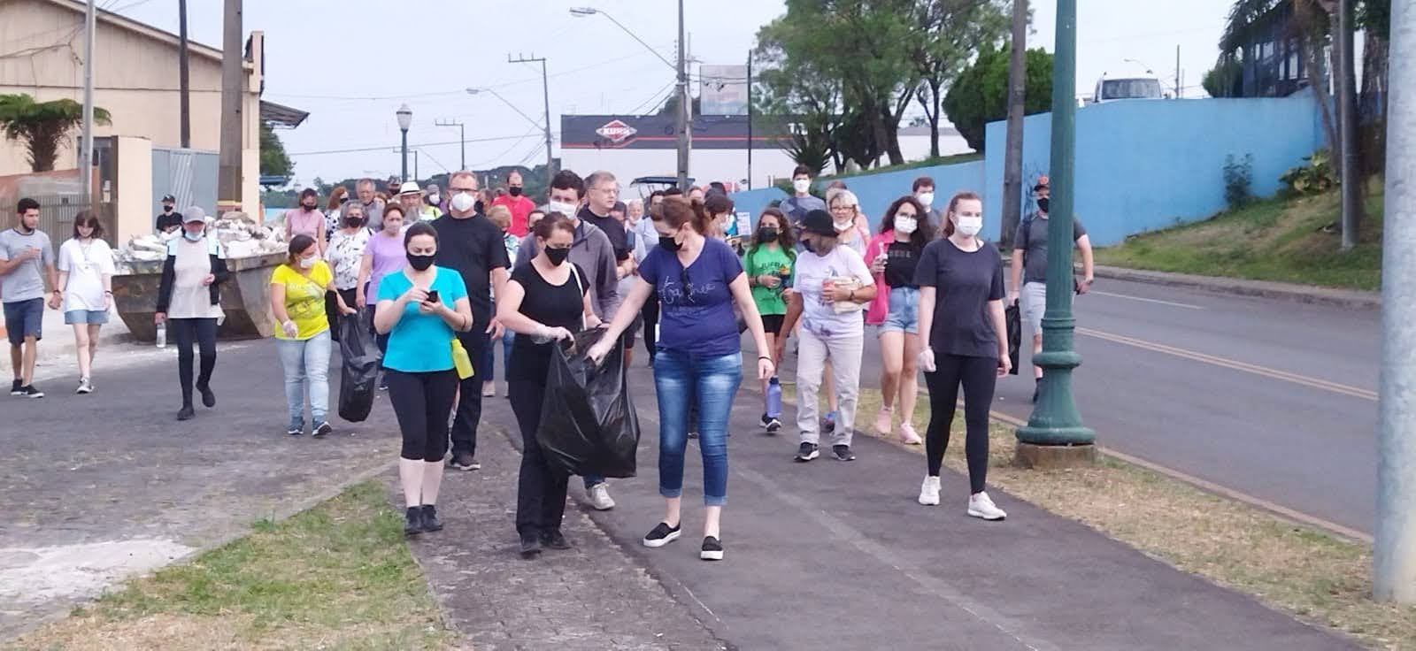 Foto de pessoas durante caminhada franciscana, recolhendo lixo em sacos nas vias públicas de Irati