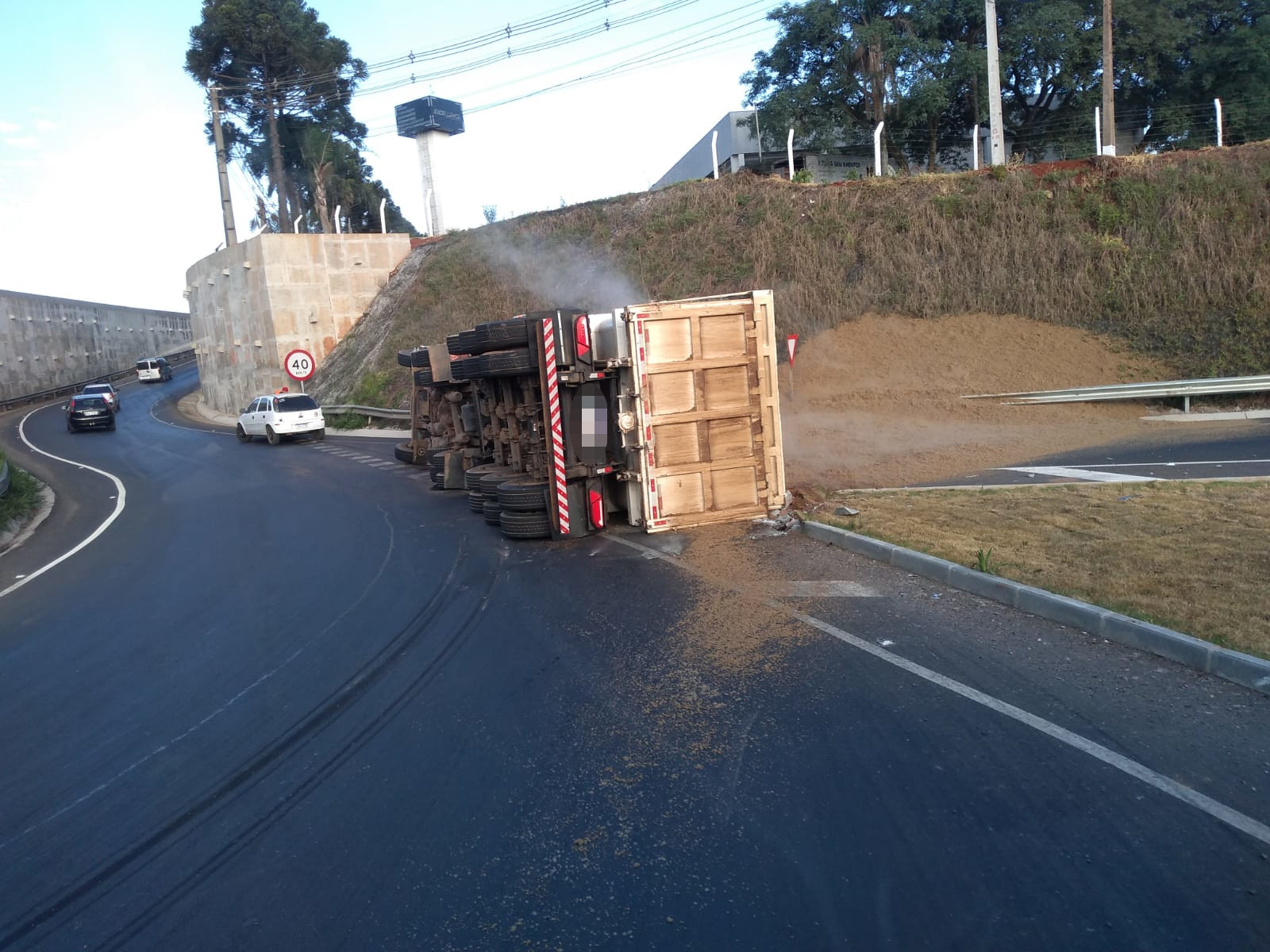 Foto de caminhão tombado sobre asfalto na BR-376, com grãos de soja espalhados pela pista