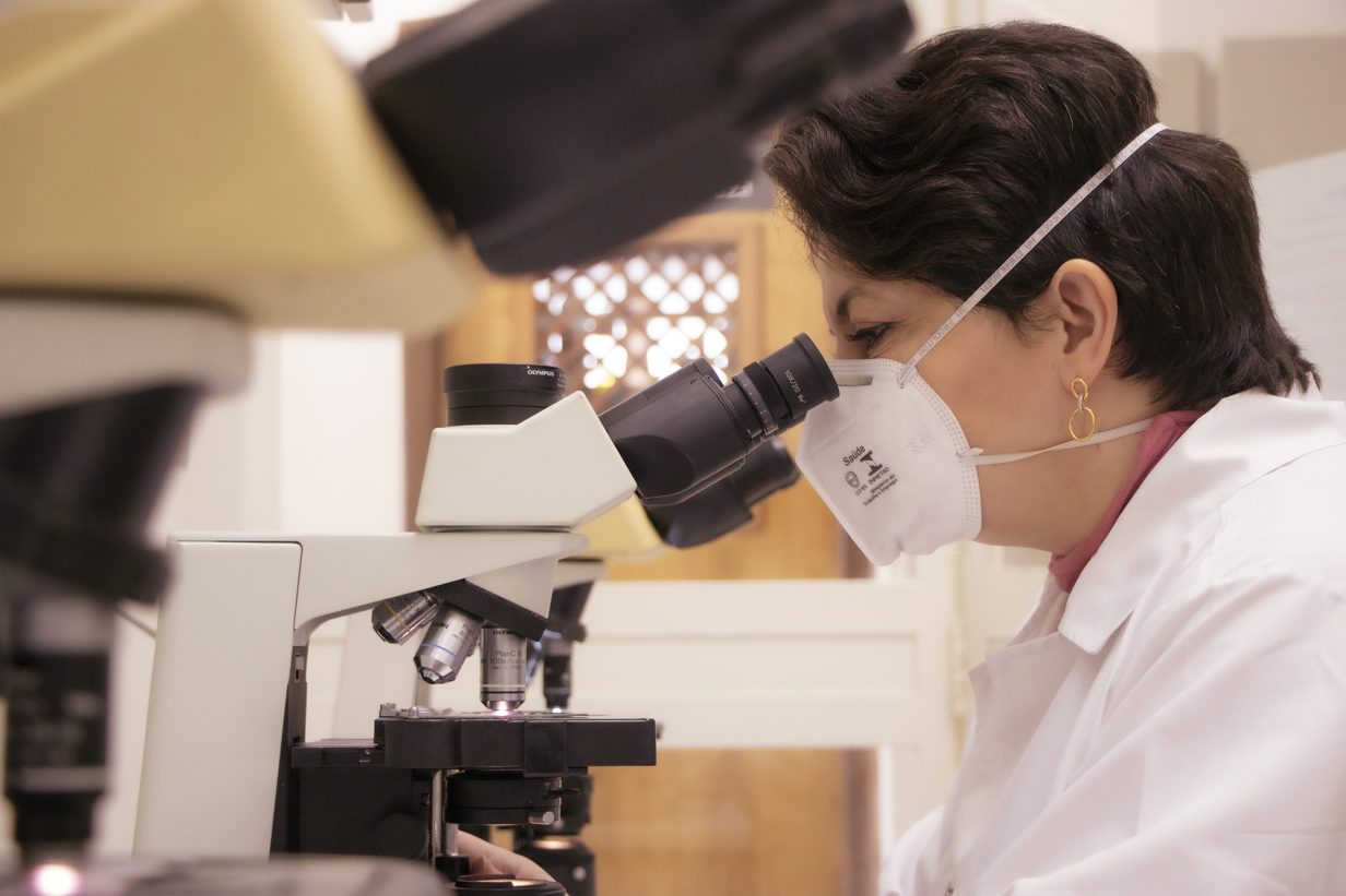 Foto da professora Elisangela Gueiber Montes, observando amostras em microscópio