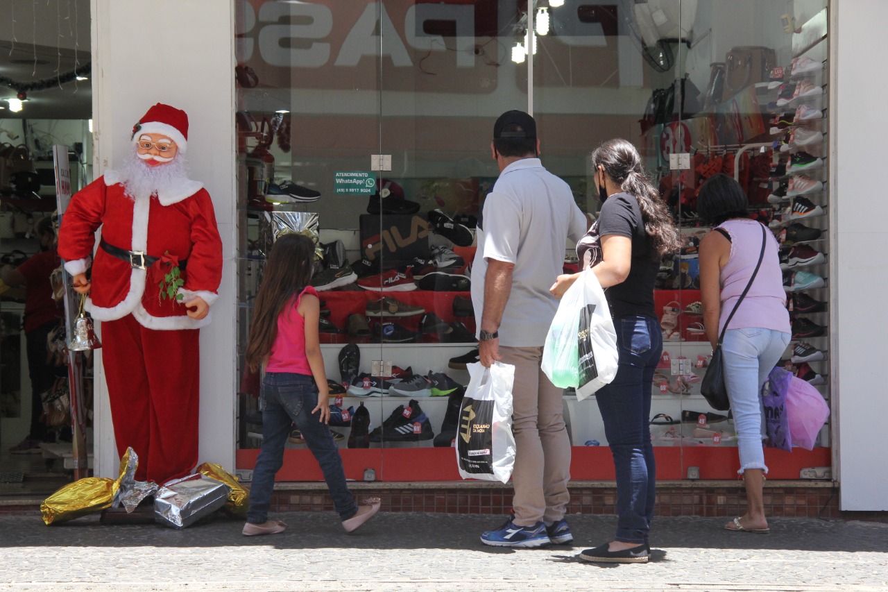 Pessoas na rua observam vitrine de Natal no comércio de Ponta Grossa