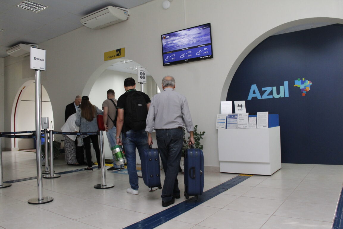 Foto pessoas com malas na fila de embarque do Aeroporto Sant'Ana, em Ponta Grossa