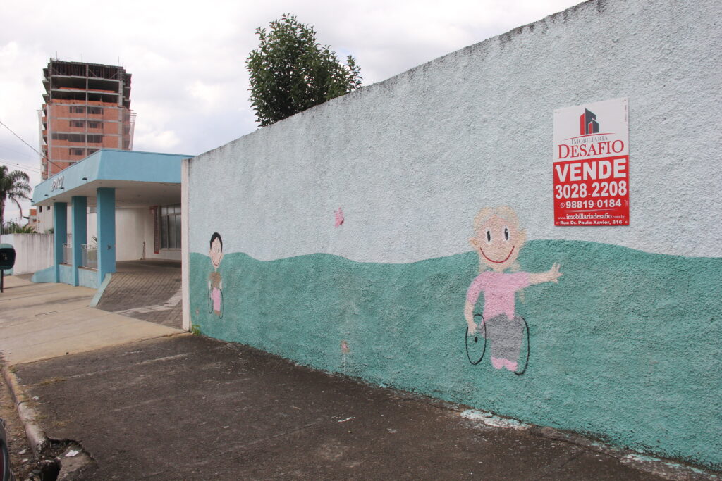 Foto do muro da APACD, indicando a venda de imóvel