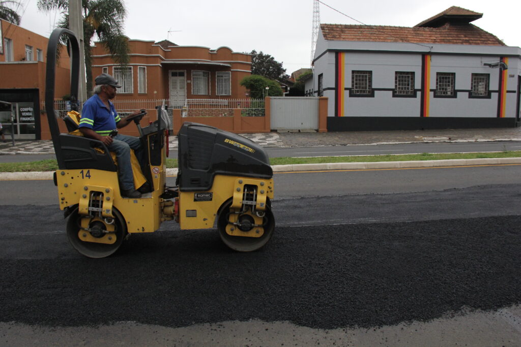 Foto de funcionários usando máquina para reparo em asfalto