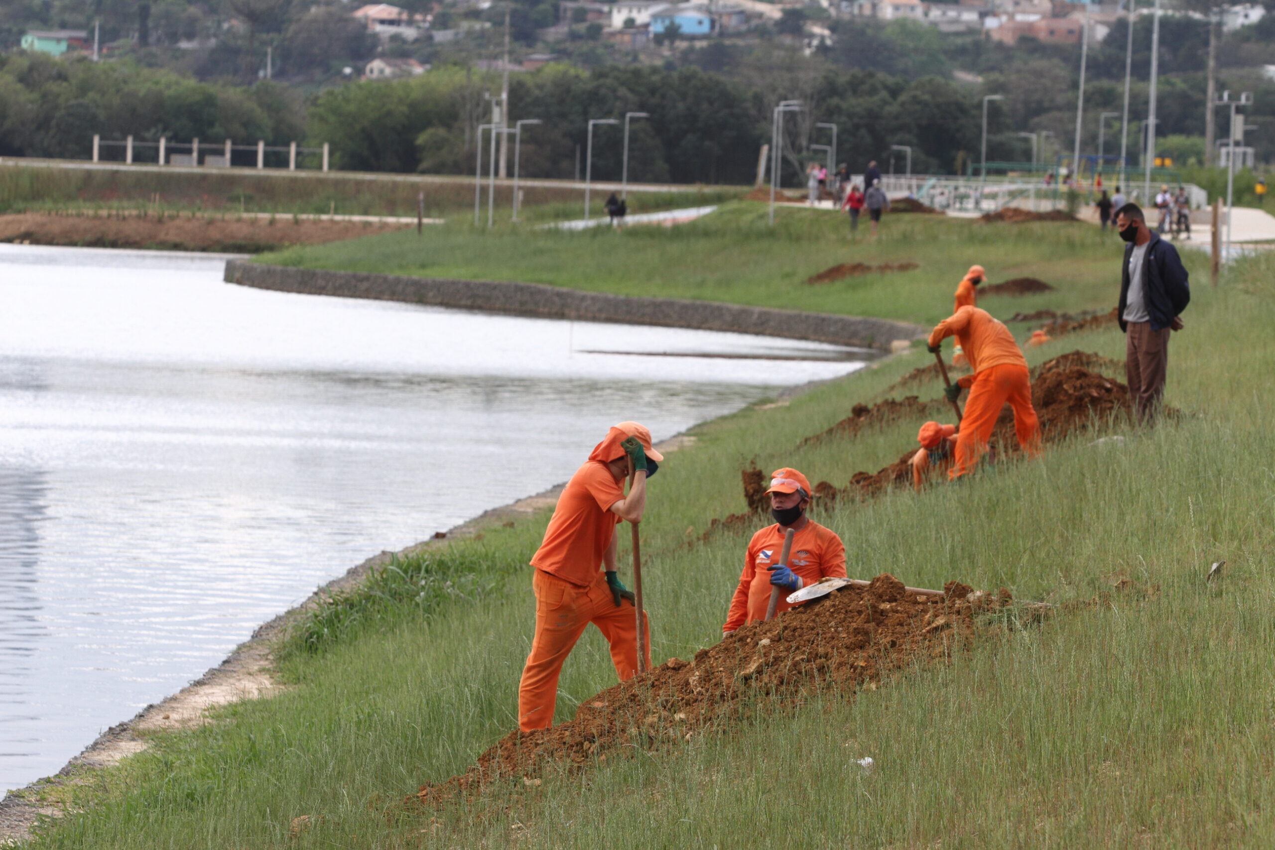 Foto de funcionários da Prefeitura de Ponta Grossa preparando plantio de mudas de árvores no entorno do Lago de Olarias