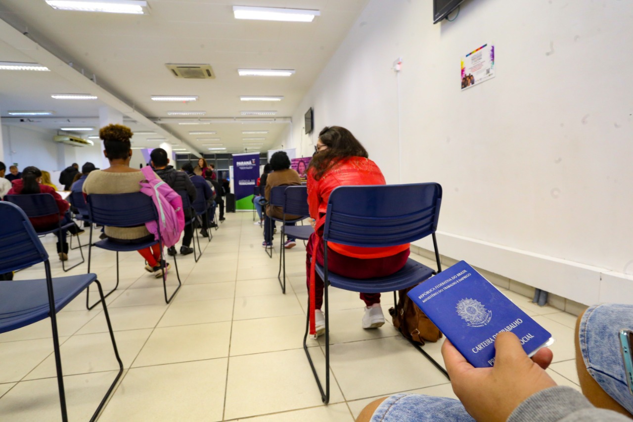 Foto de mão segurando carteira de trabalho, em agência de recrutamento