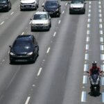 visão de uma rodovia com carros e moto na faixa azul