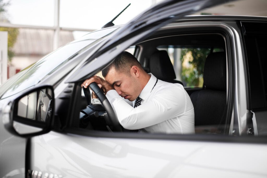 Homem com a cabeça no volante.