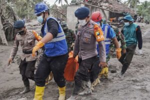Bombeiros da Indonésia carregam um corpo após a retomada da erupção do vulcão.