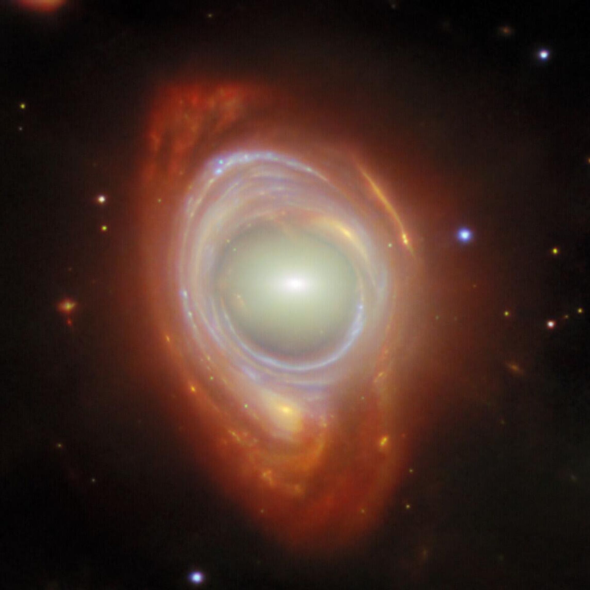 Registro do fenômeno cósmico raro chamado anel de Einstein. O que a princípio parece ser uma única galáxia de formato estranho é, na verdade, duas galáxias separadas por uma grande distância. A galáxia mais próxima do primeiro plano fica no centro da imagem, enquanto a galáxia mais distante do fundo parece estar enrolada em volta da galáxia mais próxima, formando um anel. Os anéis de Einstein ocorrem quando a luz de um objeto muito distante é curvada (ou lenteada) em torno de um objeto intermediário massivo Registro do fenômeno cósmico raro chamado anel de Einstein. O que a princípio parece ser uma única galáxia de formato estranho é, na verdade, duas galáxias separadas por uma grande distância. A galáxia mais próxima do primeiro plano fica no centro da imagem, enquanto a galáxia mais distante do fundo parece estar enrolada em volta da galáxia mais próxima, formando um anel. Os anéis de Einstein ocorrem quando a luz de um objeto muito distante é curvada (ou lenteada) em torno de um objeto intermediário massivo - Sputnik Brasil, 1920, 01.04.2025