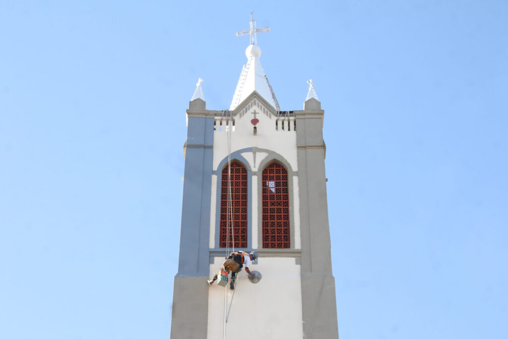Trabalhador pintando a torre da Igrejinha de Uvaranas.