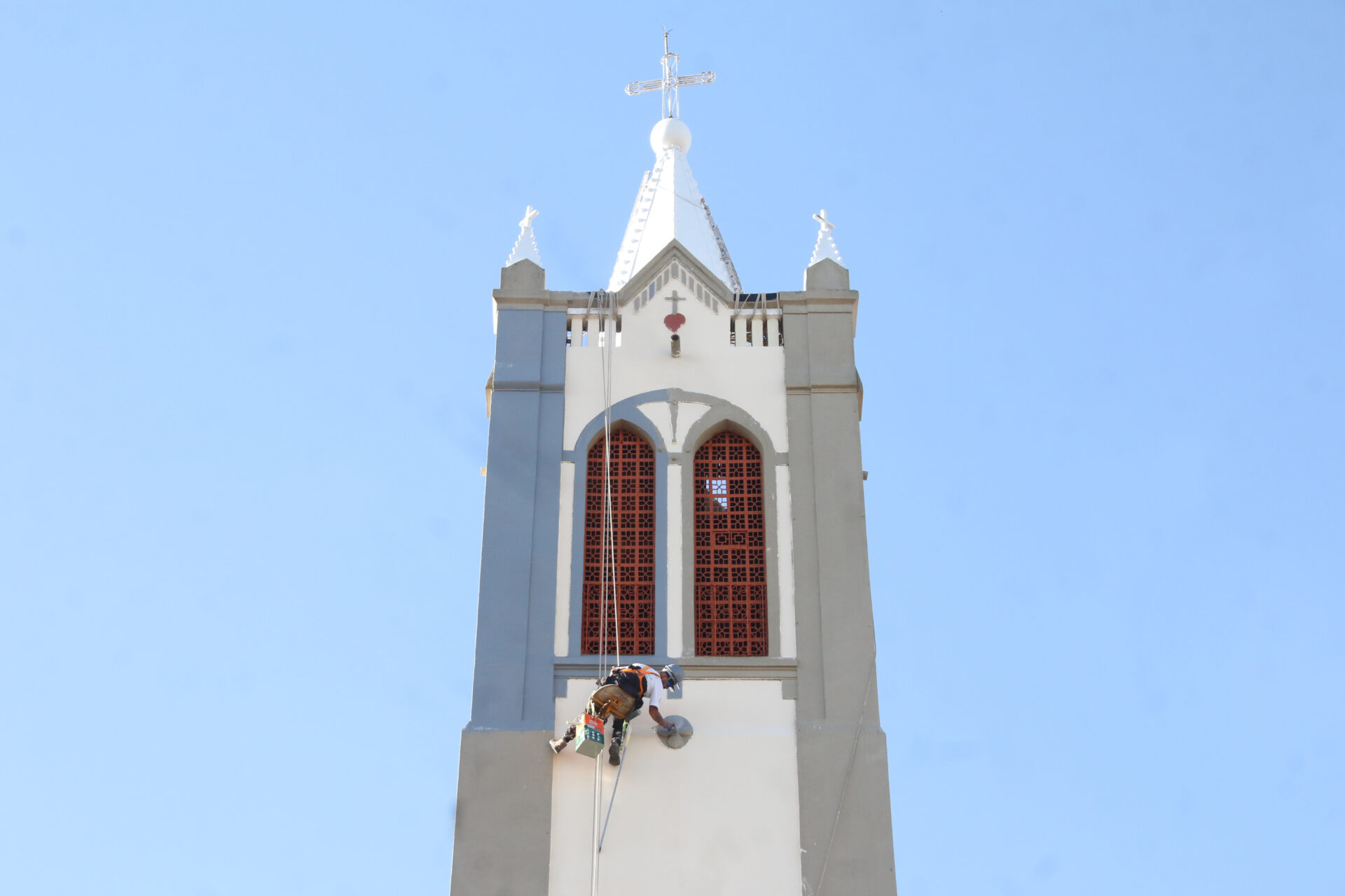 Trabalhador pintando a torre da Igrejinha de Uvaranas.
