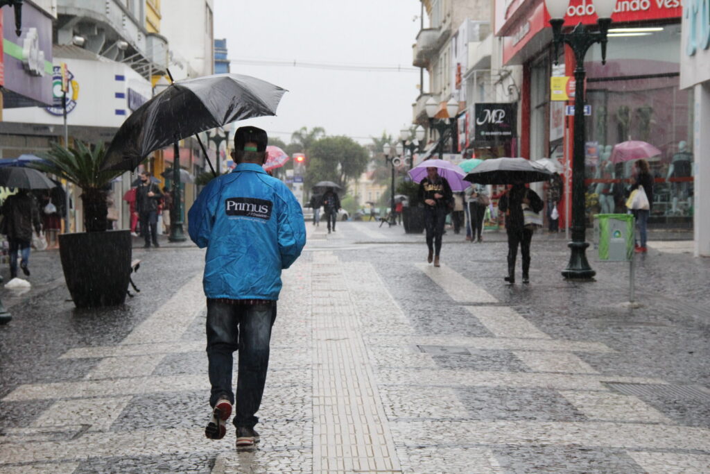 Foto de pessoa segurando guarda-chuva no calçadão de Ponta Grossa ilustra previsão do tempo