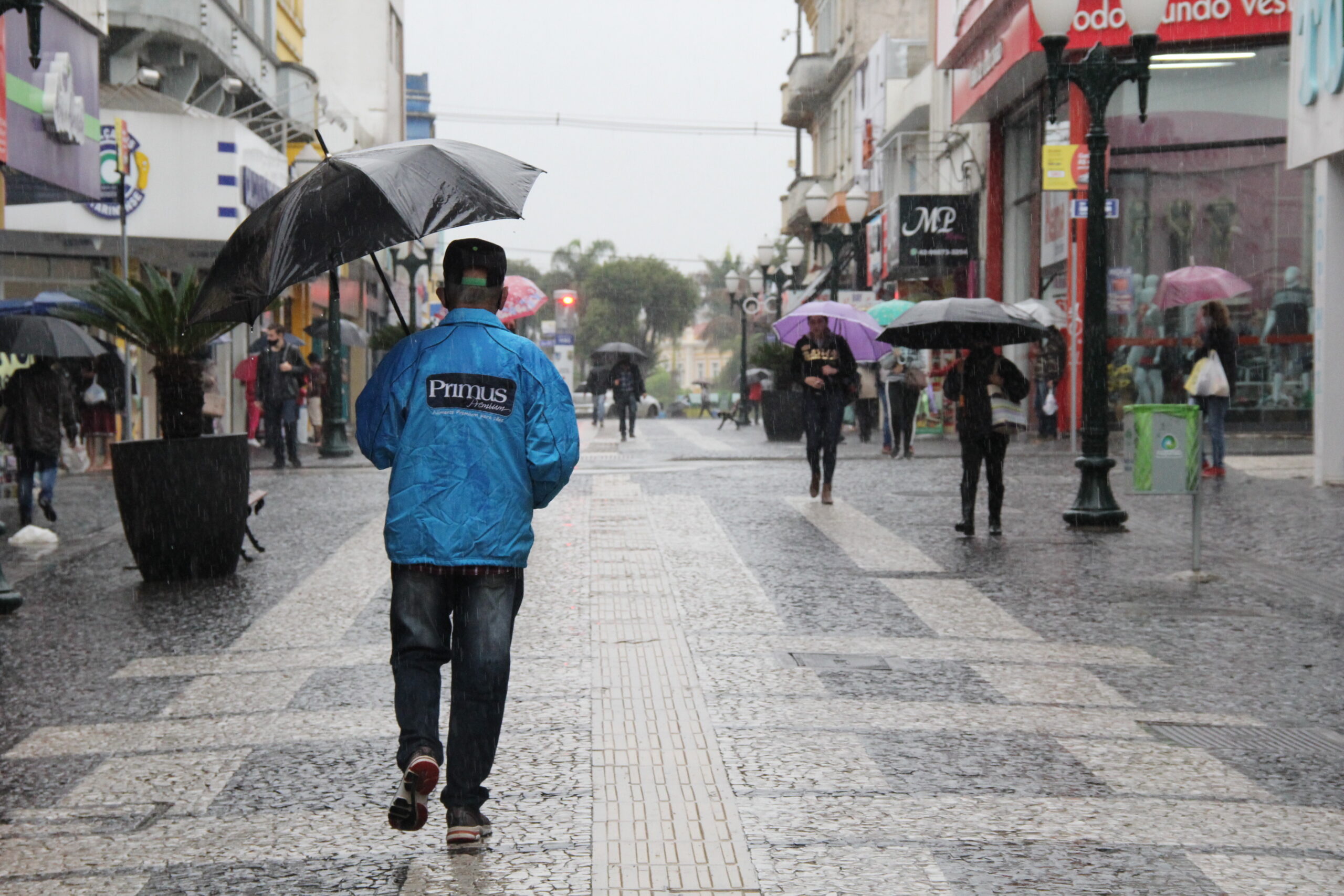Foto de pessoa segurando guarda-chuva no calçadão de Ponta Grossa ilustra previsão do tempo