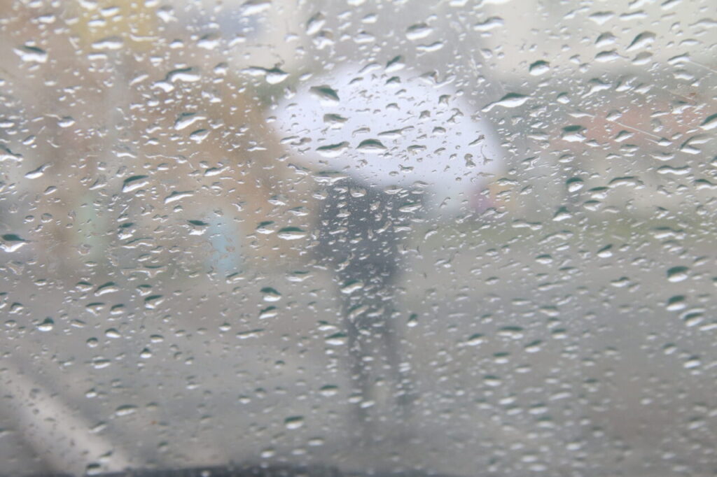 Vidro molhado e pedestre com guarda-chuva ilustram a Previsão do tempo do Simepar