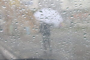 Vidro molhado e pedestre com guarda-chuva ilustram a Previsão do tempo do Simepar