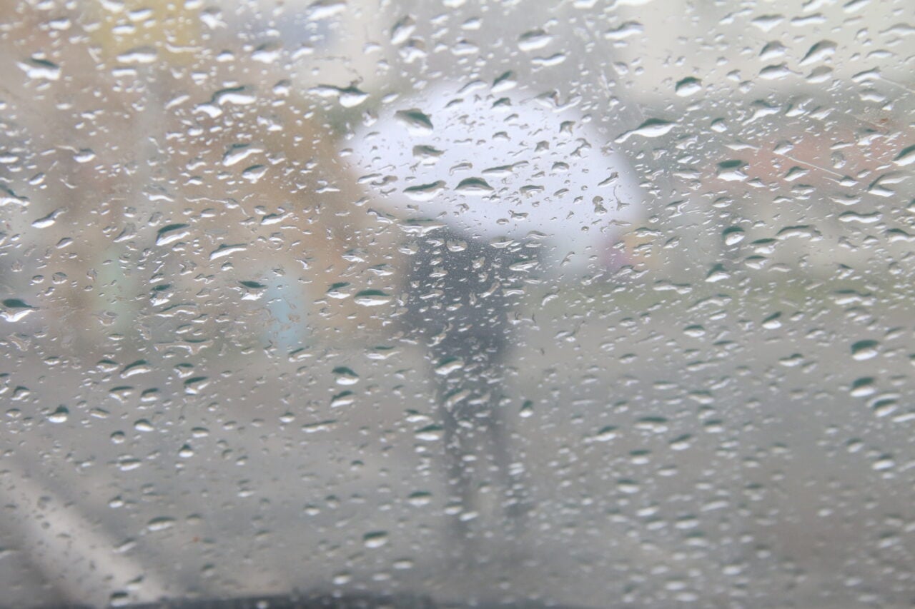 Vidro molhado e pedestre com guarda-chuva ilustram a Previsão do tempo do Simepar