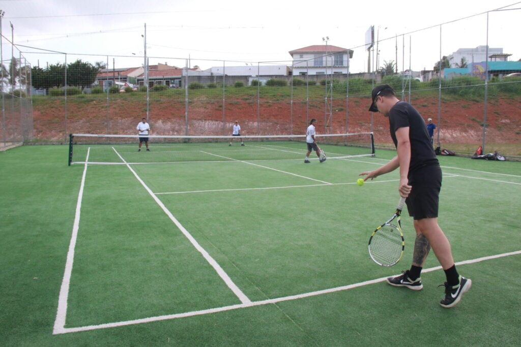 Tenista se prepara para sacar em jogo de duplas na quadra do Lago de Olarias.