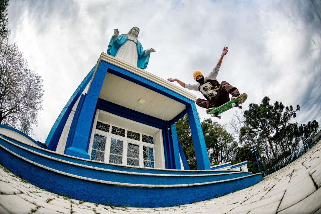 Atleta flutua sobre skate, tendo ao fundo a imagem de uma santa, em Irati, Paraná