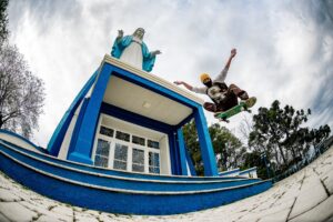 Atleta flutua sobre skate, tendo ao fundo a imagem de uma santa, em Irati, Paraná
