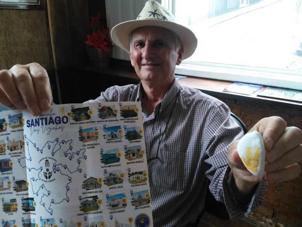 Elcir Francisco Amadei, segurando um mapa e uma pedra que representa o Caminho de Santiago