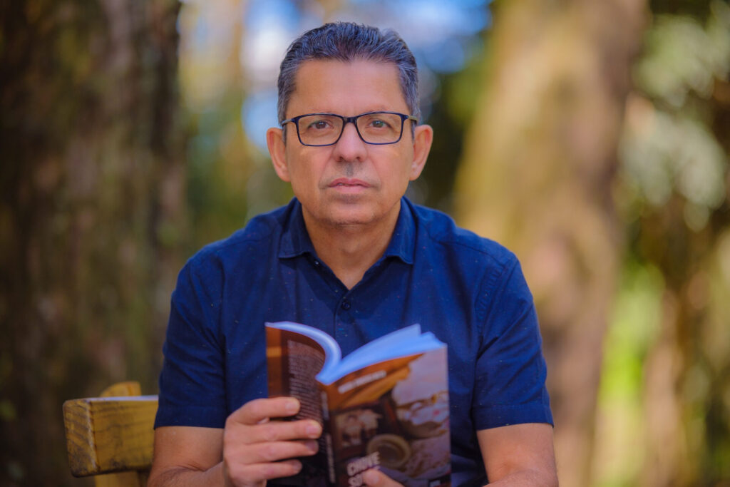 Escritor Miguel Sanches Neto, segurando livro de própria autoria