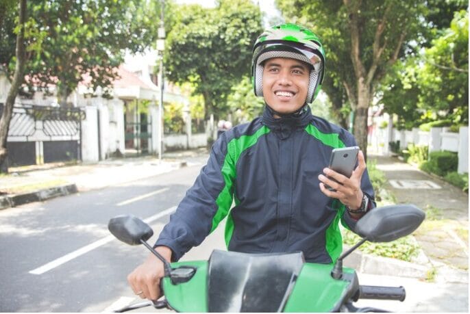 Motorista de táxi da motocicleta que toma a ordem através do aplicativo on-line do telefone móvel