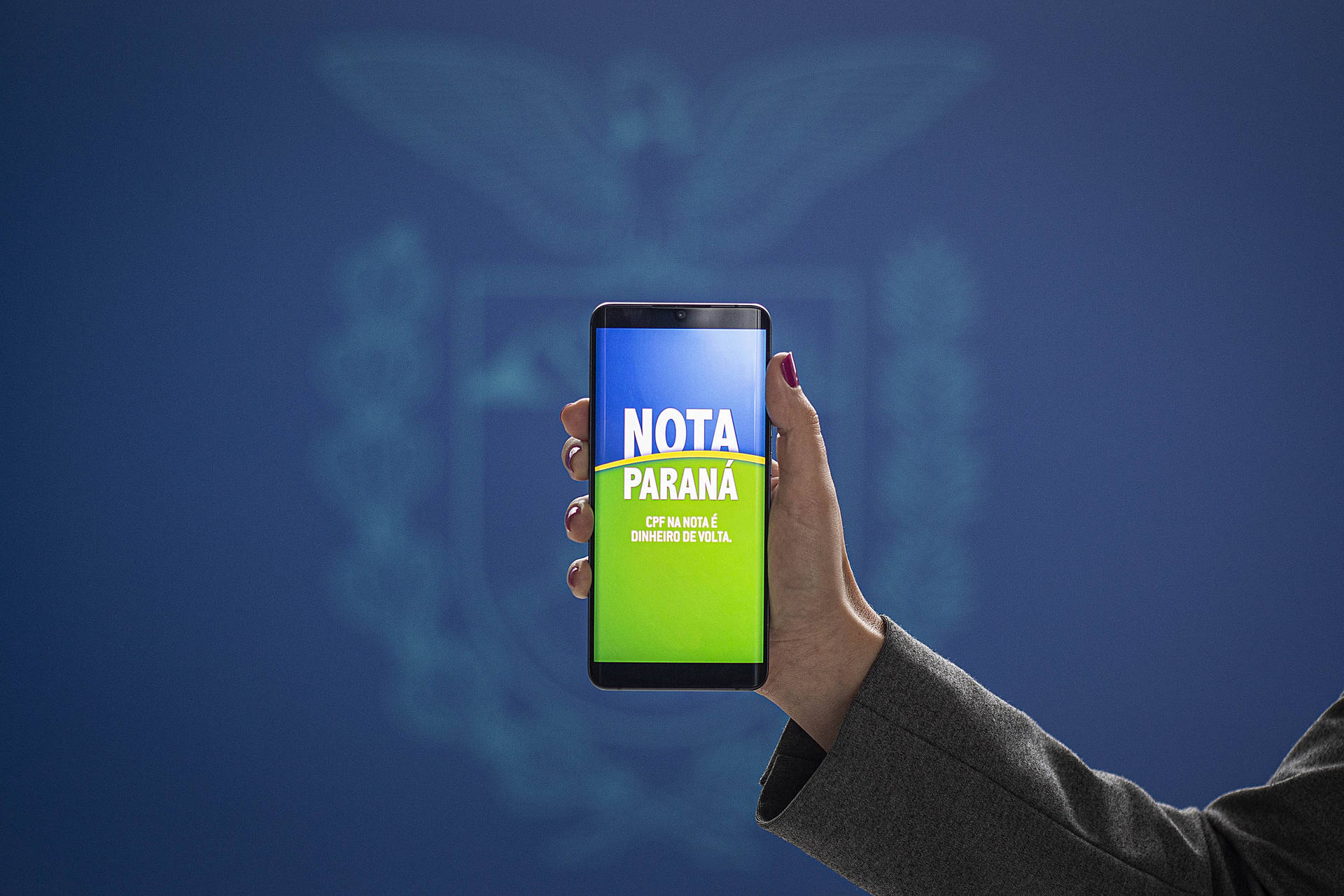 Uma pessoa segurando um celular com a mensagem Nota Paraná na tele.