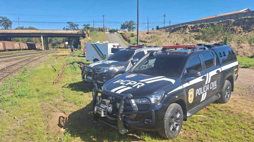 Viaturas da Polícia Civil do Paraná estacionadas em área de pátio de manobras de ferrovia em Ponta Grossa