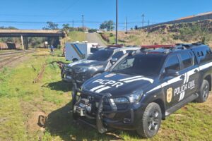 Viaturas da Polícia Civil do Paraná estacionadas em área de pátio de manobras de ferrovia em Ponta Grossa