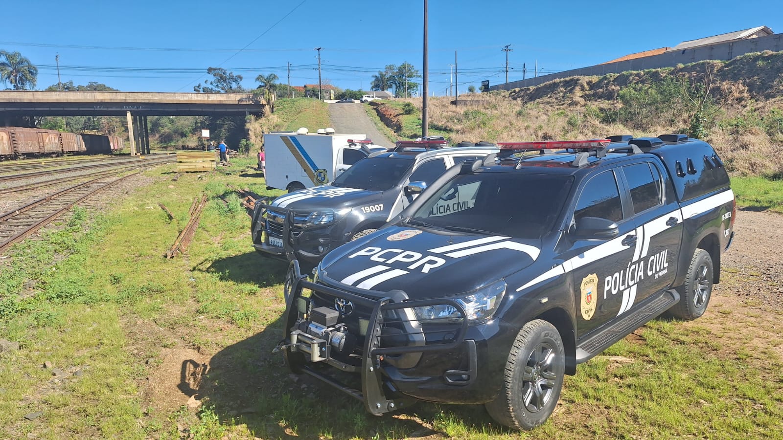 Viaturas da Polícia Civil do Paraná estacionadas em área de pátio de manobras de ferrovia em Ponta Grossa