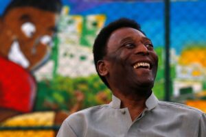 Ex-jogador Pelé sentado sorrindo em conversa.