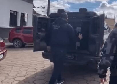Policiais abrem viatura para retirar o preso do camburão