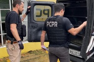 Policiais civis com camburão aberto em frente à delegacia de Carambeí