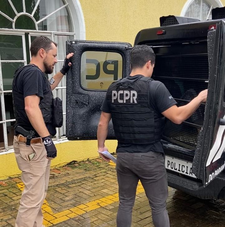 Policiais civis com camburão aberto em frente à delegacia de Carambeí