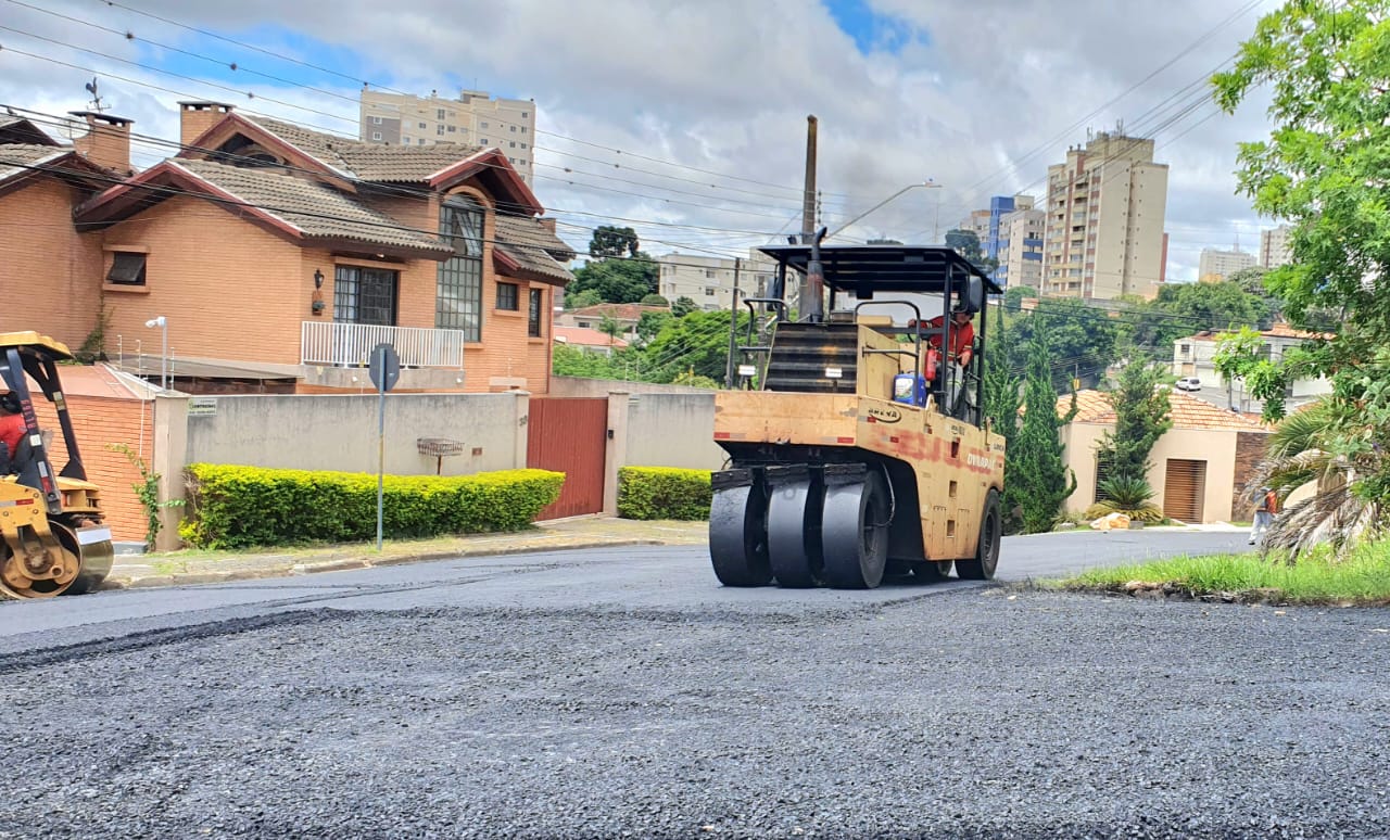 Máquina e operador trabalhando por asfalto novo em rua de PG