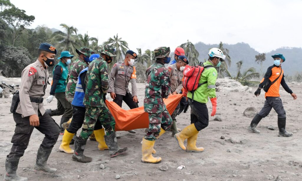 Bombeiros da Indonésia carregam um corpo após a retomada da erupção do vulcão.