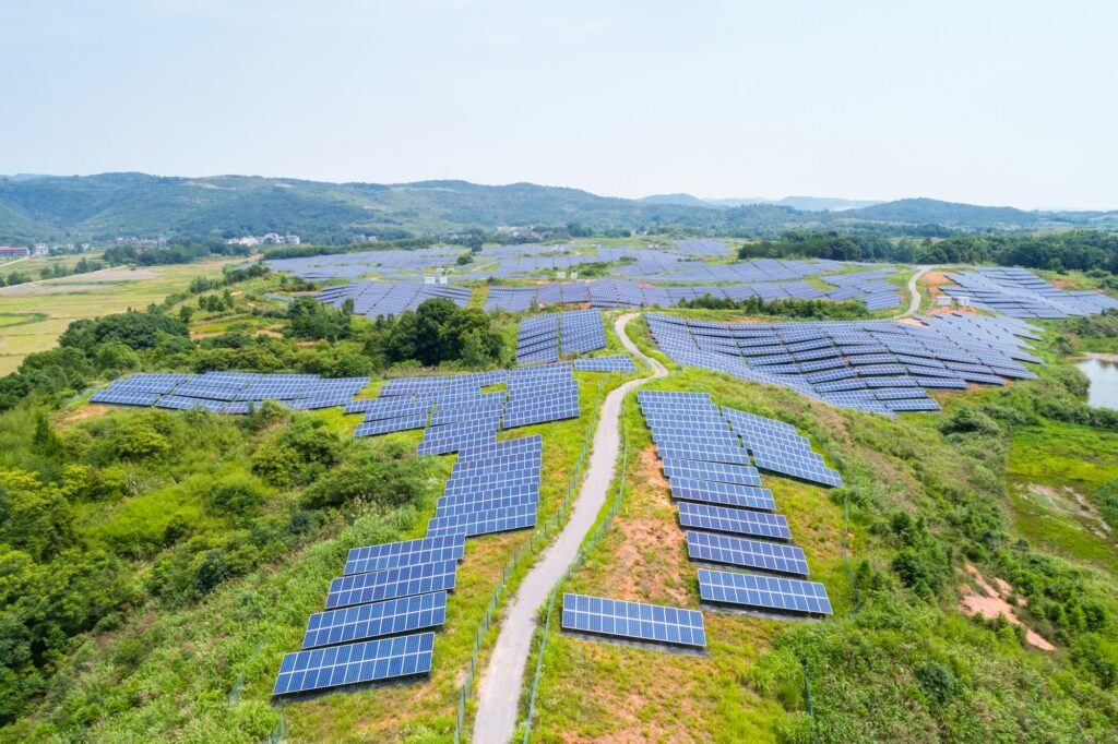 Uma imagem aérea de uma fazenda solar, repleta de painéis fotovoltáicos