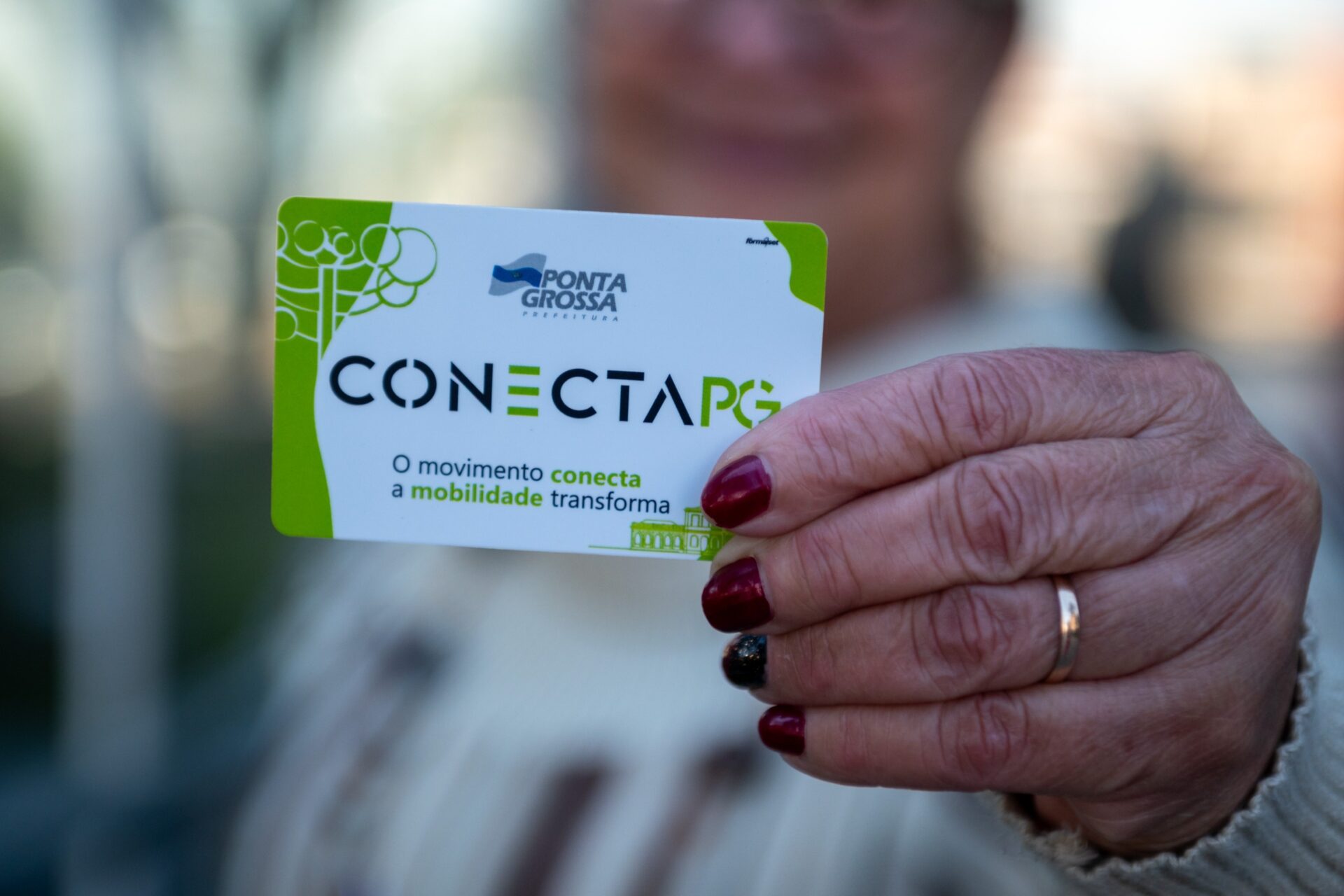 Mulher segurando o cartão Conecta PG para usuários de 60 e mais anos