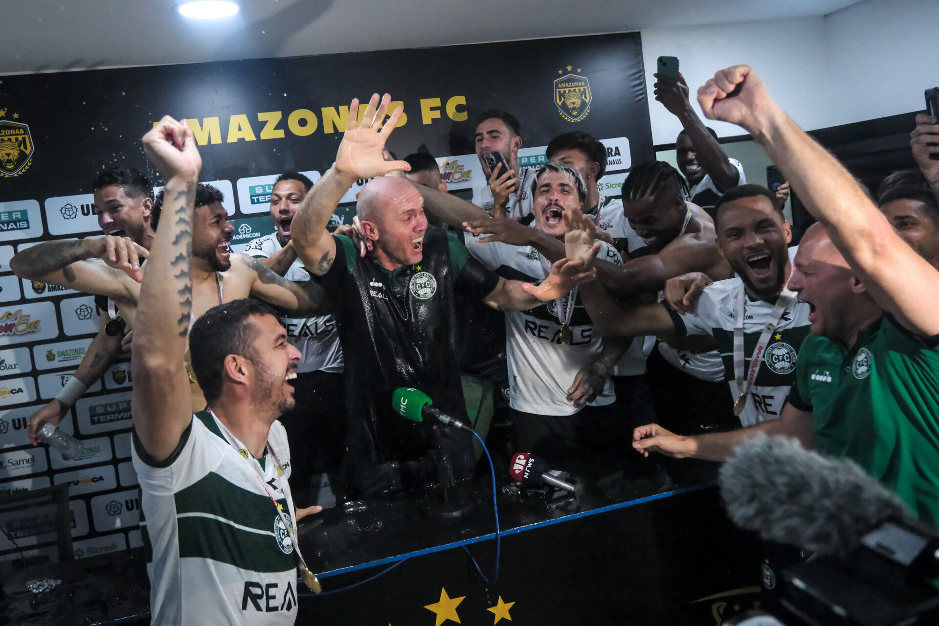 Comemoração de jogadores do Coritiba com o técnico Mozart, em sua coletiva pós-jogo do título da Série B 2025.