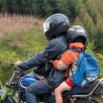 Motociclista que transporta criança