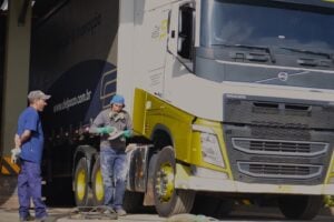 Caminhoneiro ao lado do veículo, conversando com fiscal de entregas