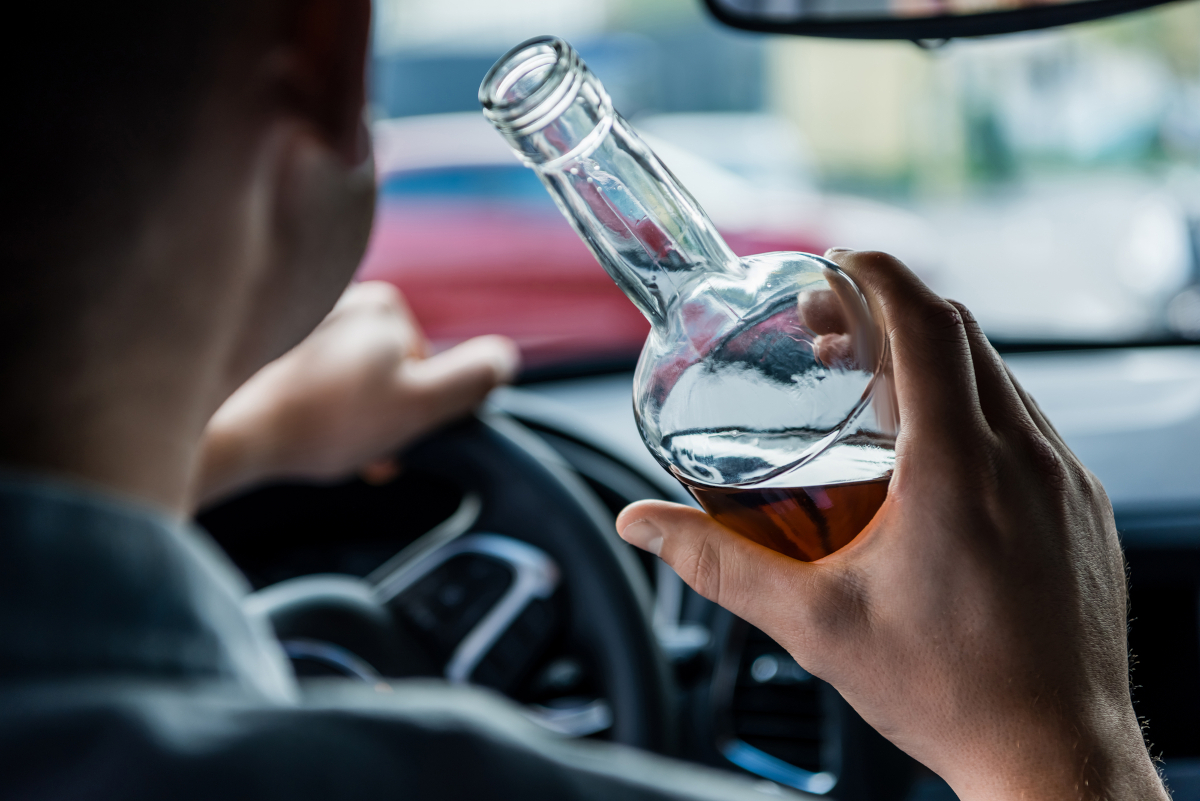 Motorista segura garrafa de bebida enquanto dirige