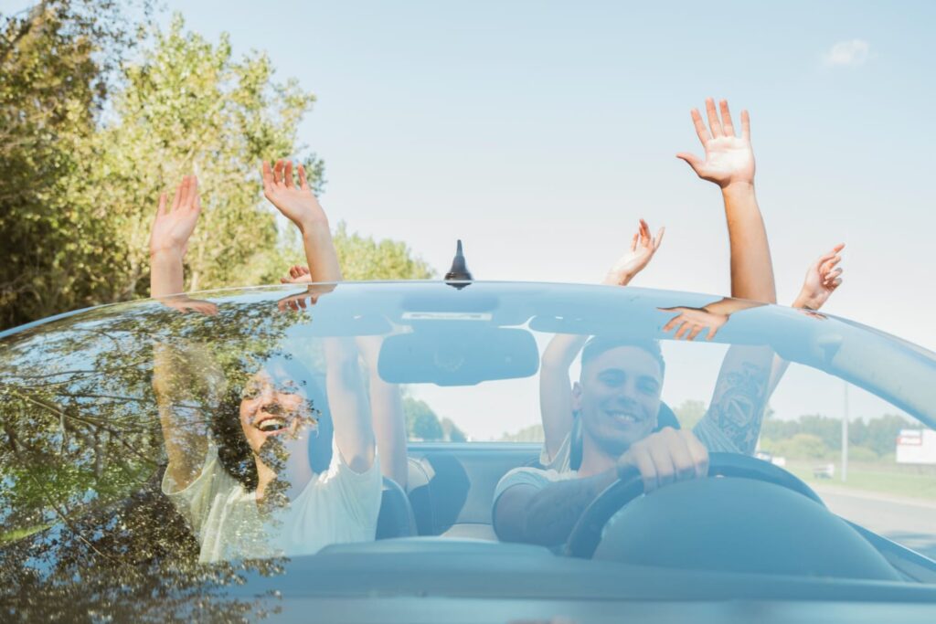 grupo-de-amigos-levantando-os-bracos-no-carro