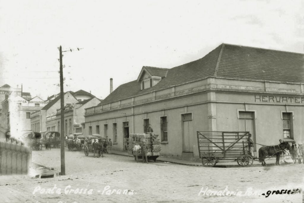 Carroceiros estacionados na Rua Benjamin Constant, em Ponta Grossa. Possivelmente nos anos 1930. Ao fundo, a Hervateria Pontagrossense