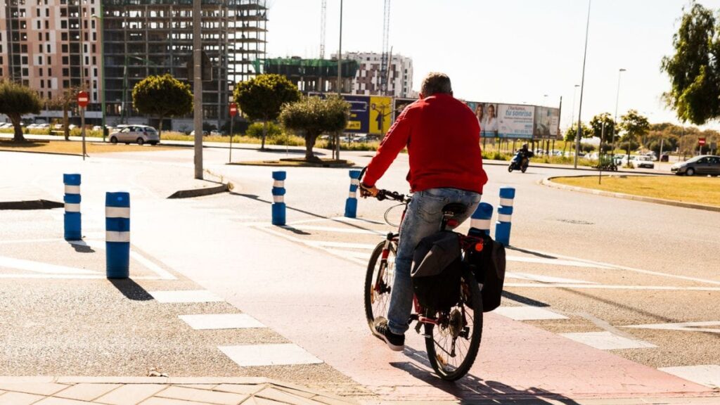 Homem de meia idade atravessa rua pedalando na ciclofaixa