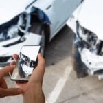 visão de uma pessoa segurando tirando foto de dois carros batidos